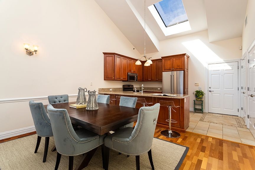 Dining area and kitchen with stainless steel appliances, high ceilings and skylight