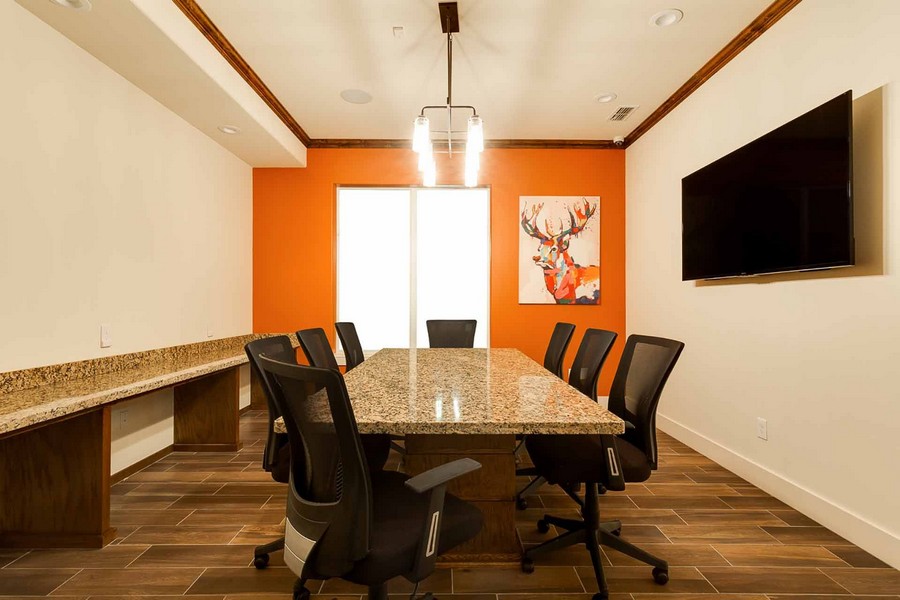 Business center with conference table, chairs, and TV