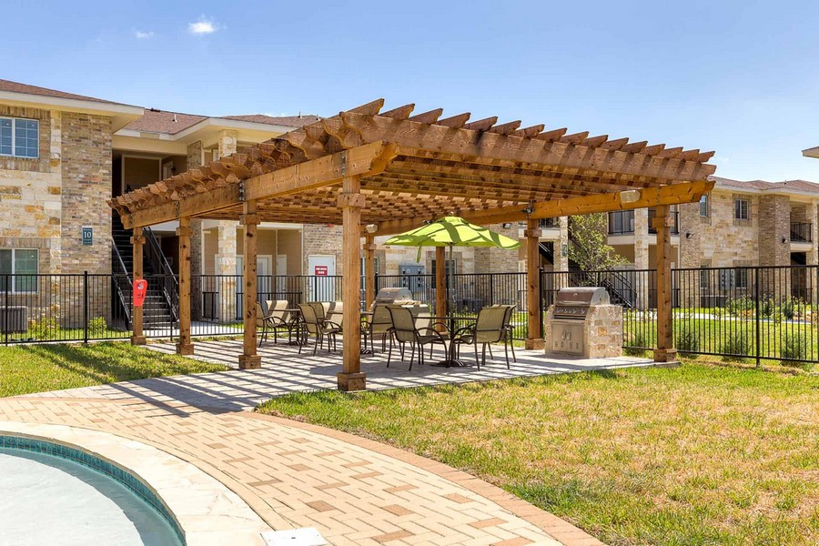 Outdoor semi-covered grilling area with two grills, tables, and chairs