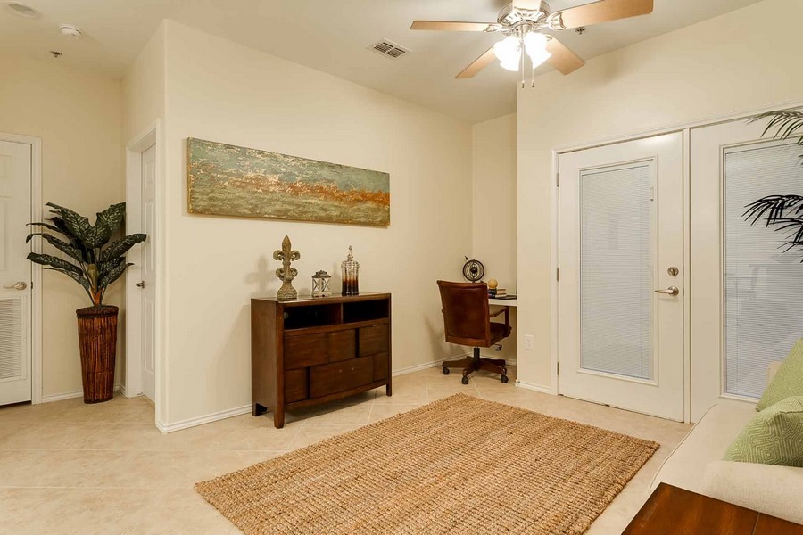 Apartment interior with area rug, desk nook, shelf against wall, and ceiling fan
