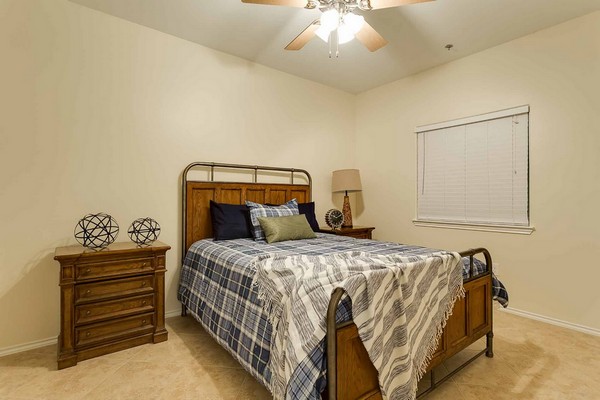 Bedroom with tile floor and bed with throw blanket on one corner. Click to view the photo gallery.