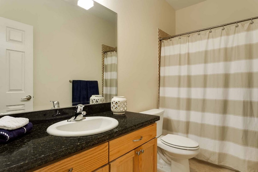 Bathroom showing sink with granite countertop and shower with striped curtain