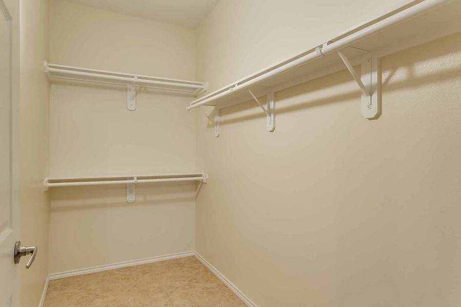 Large empty walk-in closet with shelves and racks for hangers