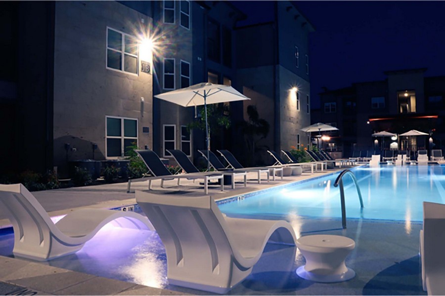 Night view of tanning ledge, swimming pool, and sun deck