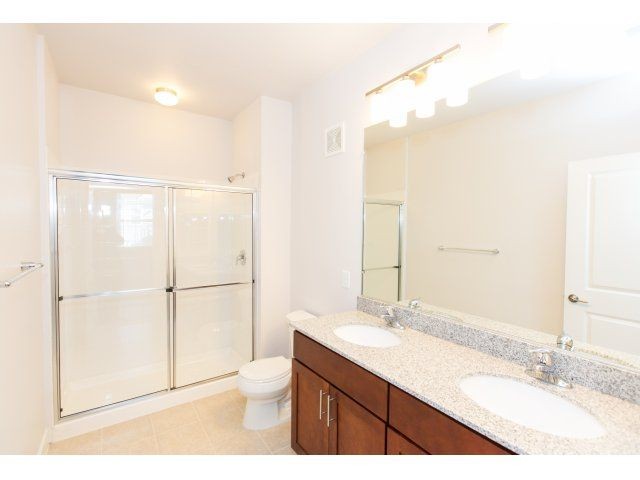 apartment bathroom with dual vanity and glass standing shower