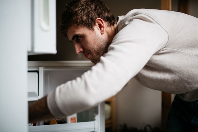 Young man looking inside refrigerator