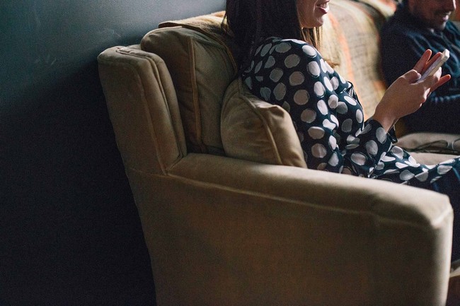 Woman sitting on couch using smartphone